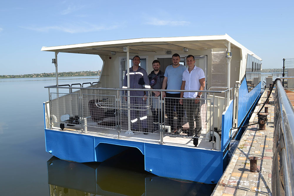Blue steel passenger catamaran alongside a quay